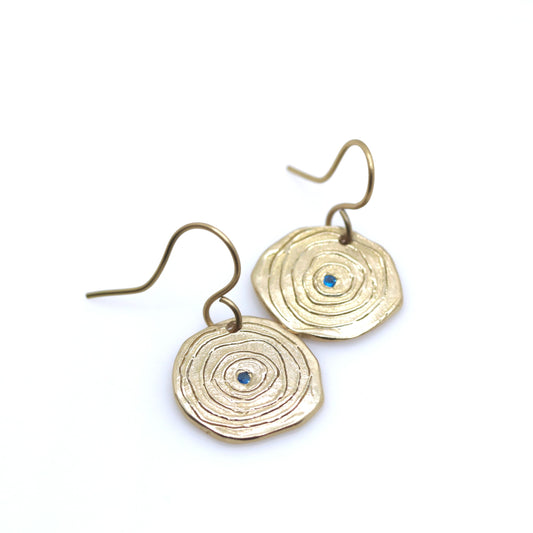 Gold circular earrings with blue stones on a white background