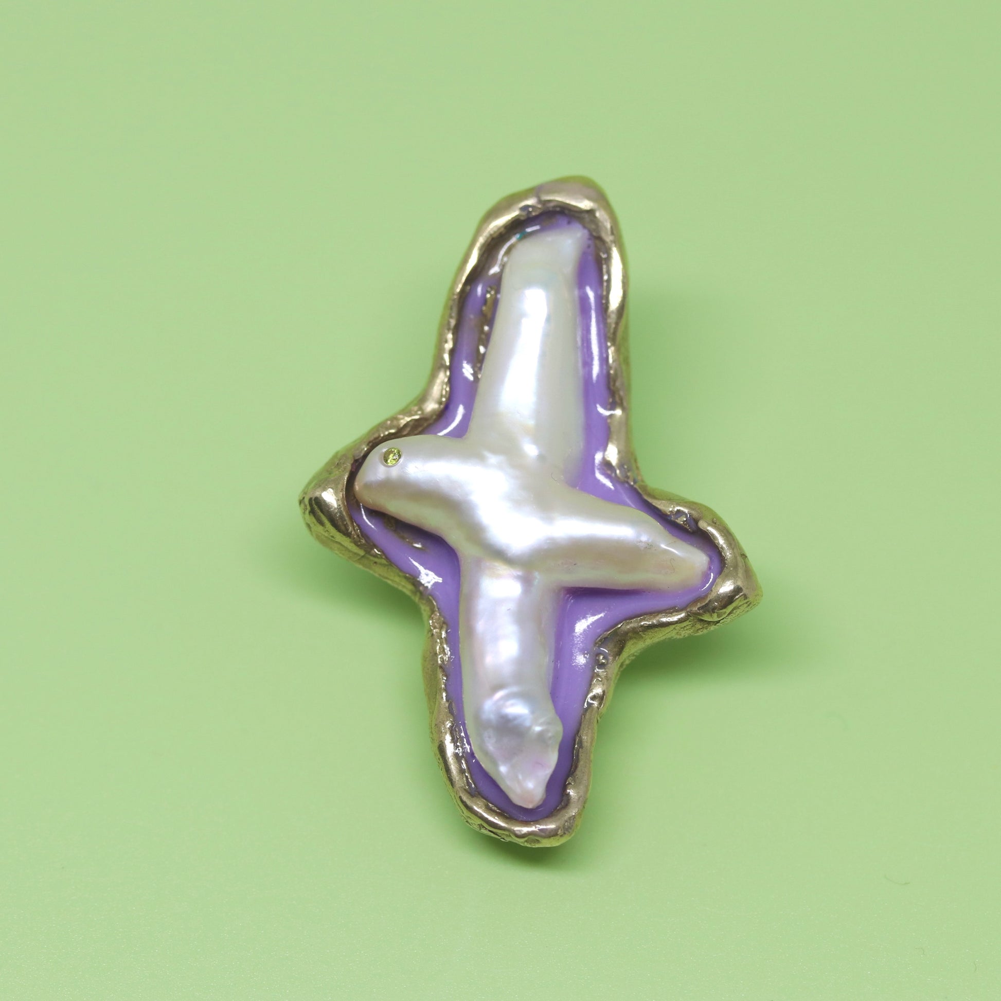 A handmade brooch of bronze, pearl and resin