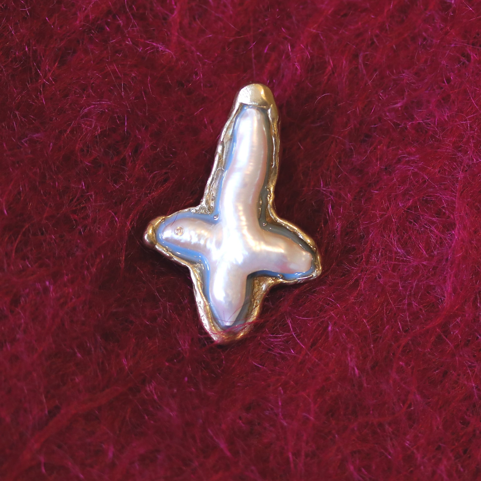A handmade brooch of bronze, pearl and resin