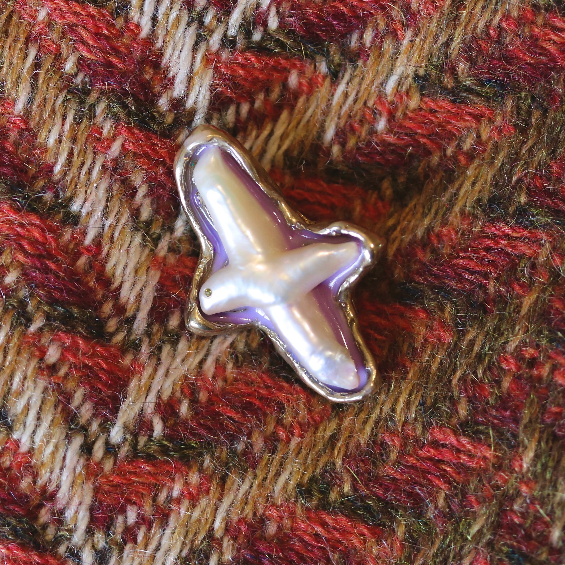 A handmade brooch of bronze, pearl and resin