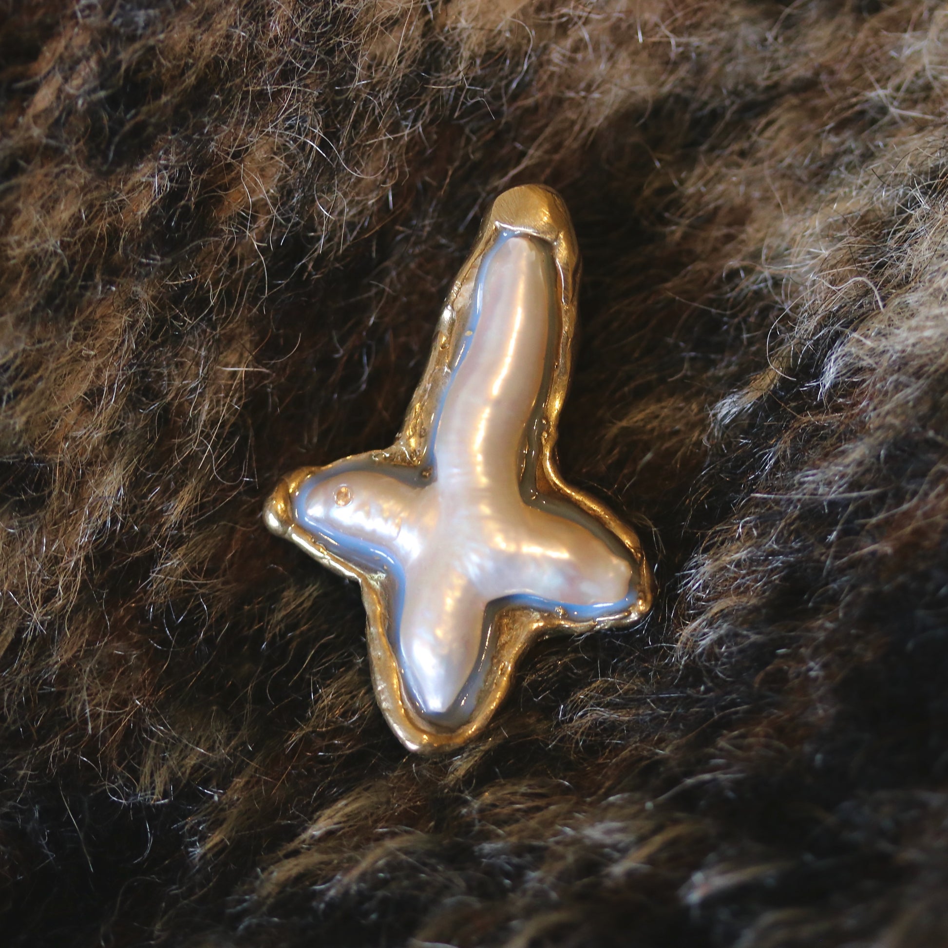 A handmade brooch of bronze, pearl and resin