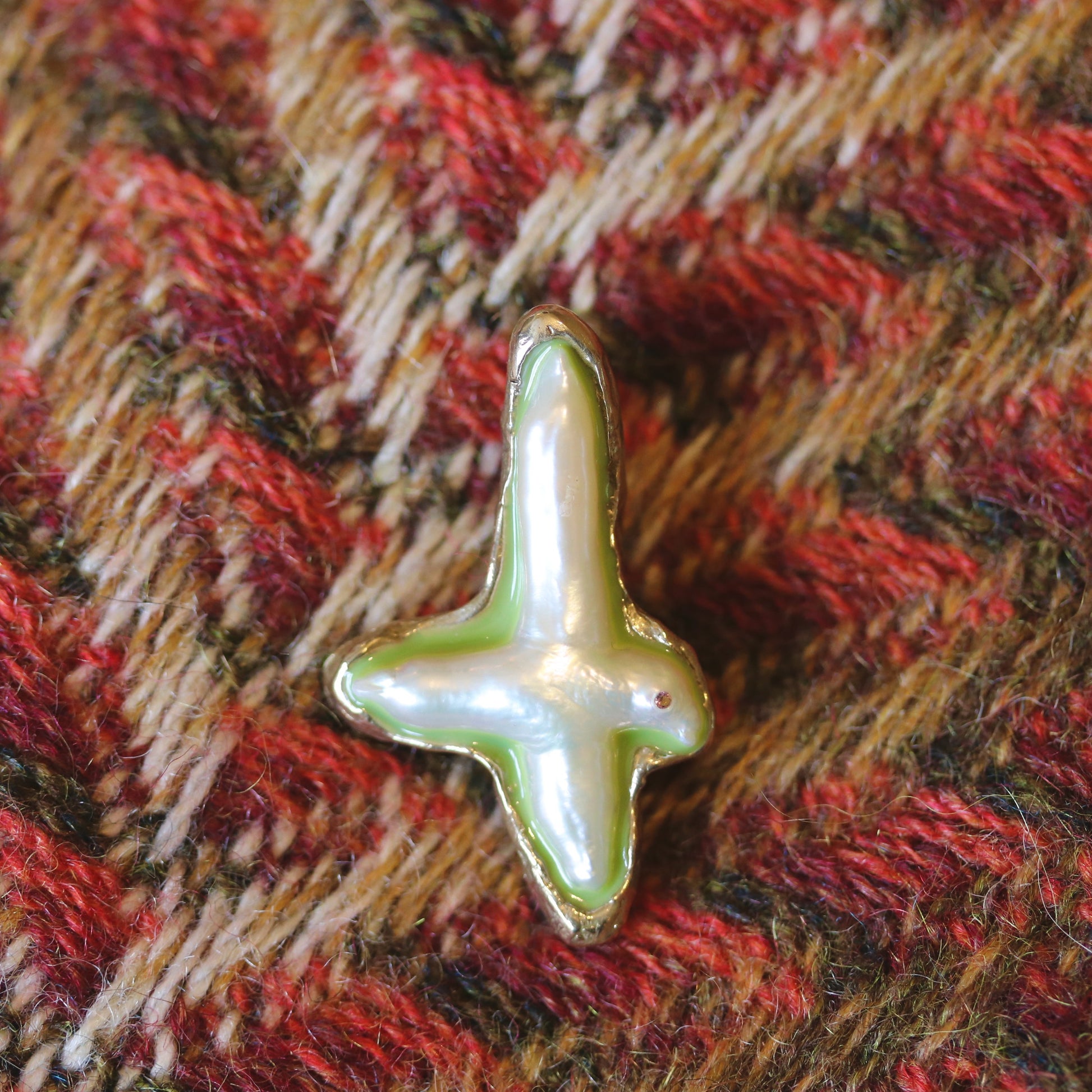 A handmade brooch of bronze, pearl and resin