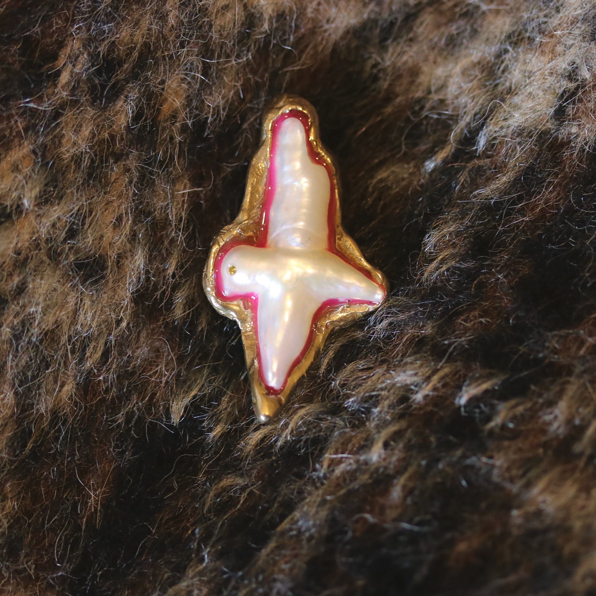 A brooch made of bronze, pearl and resin