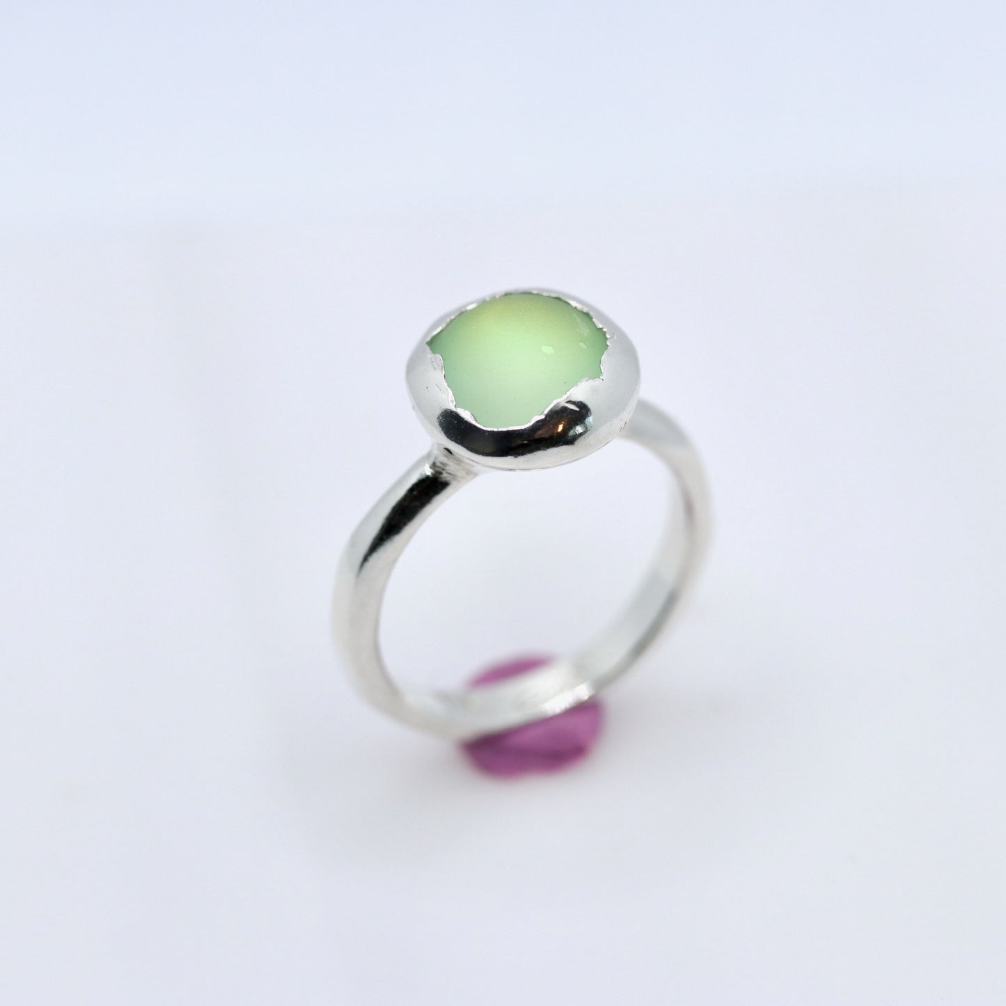 Silver ring with a green gemstone on a white background