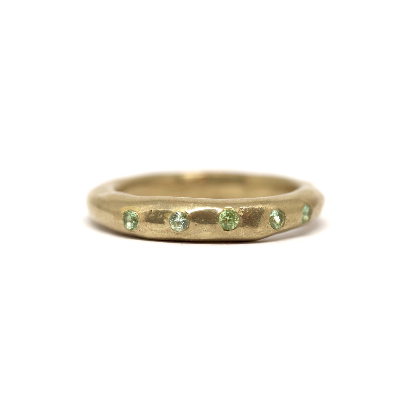 Bronze ring with green gemstones on a white background