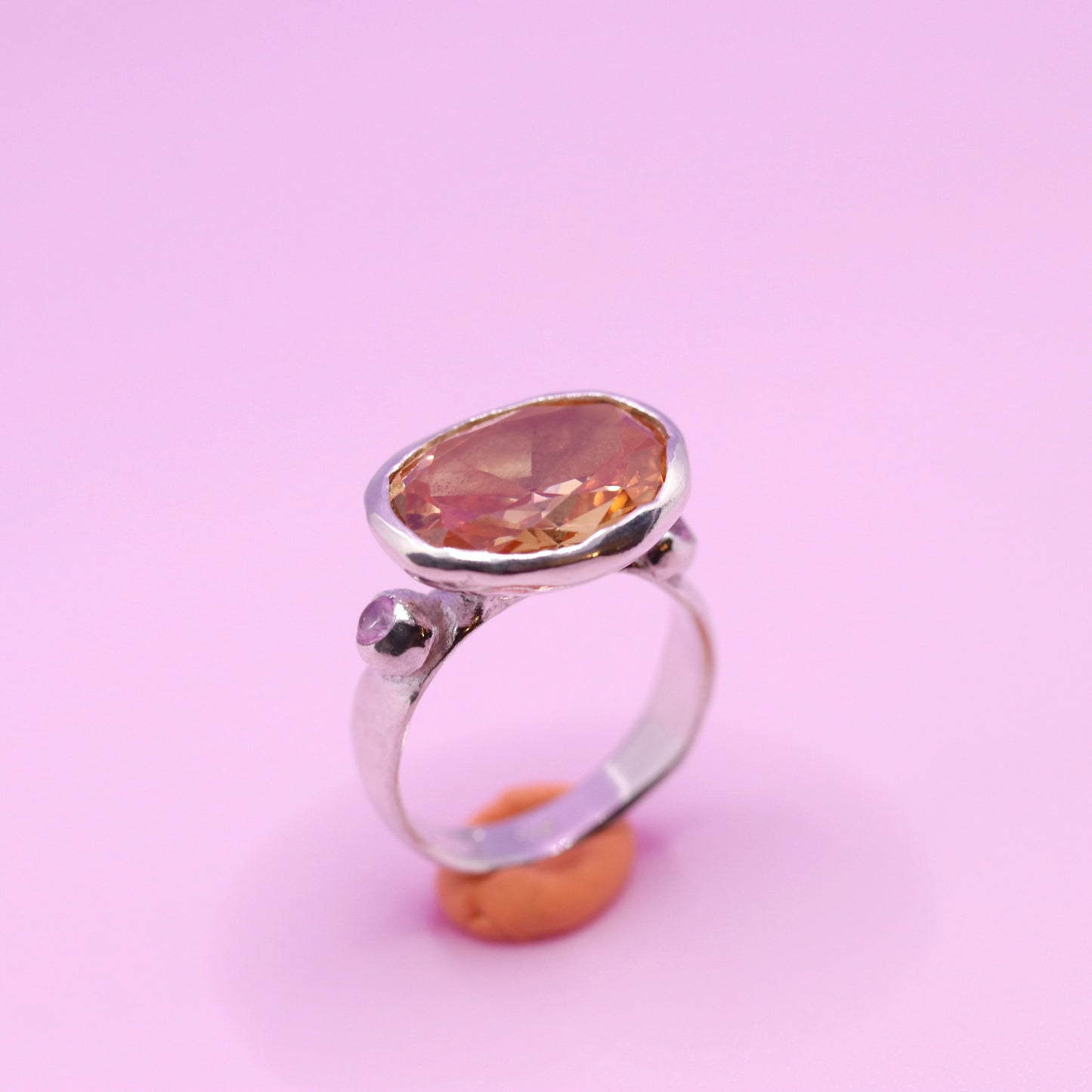 Silver ring with a large peach gemstone on a pink background. New Zealand made jewellery designer