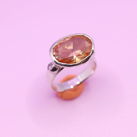 Silver ring with a large peach gemstone on a pink background. New Zealand made jewellery designer