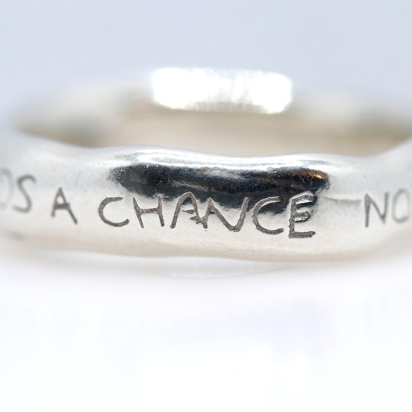 Silver ring with engraved text on a white background