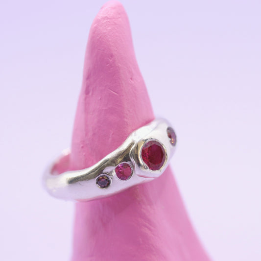 Silver ring with red gemstones on a pink background