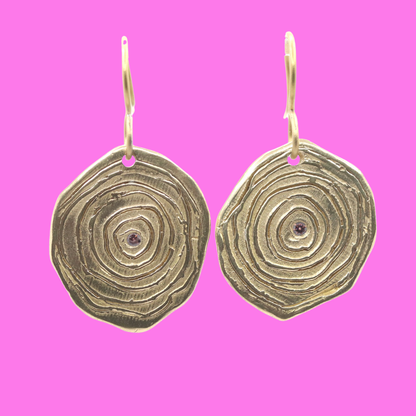 Gold earrings on a pink background