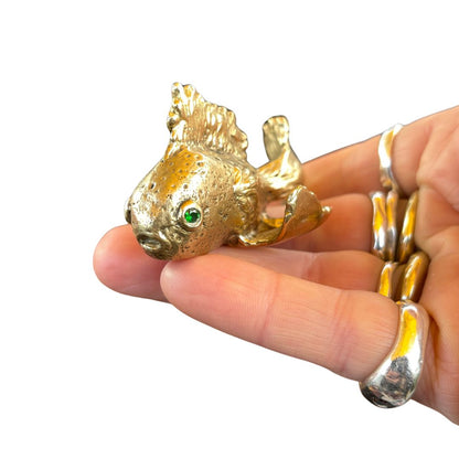 Gold fish sculpture  held in a hand with a white background