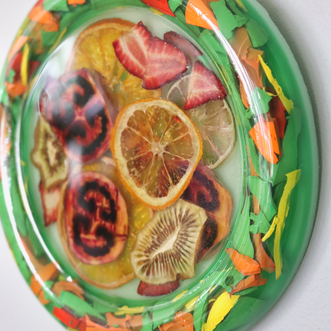 Decorative plate with sliced dehydrated fruits and colorful design on a white background