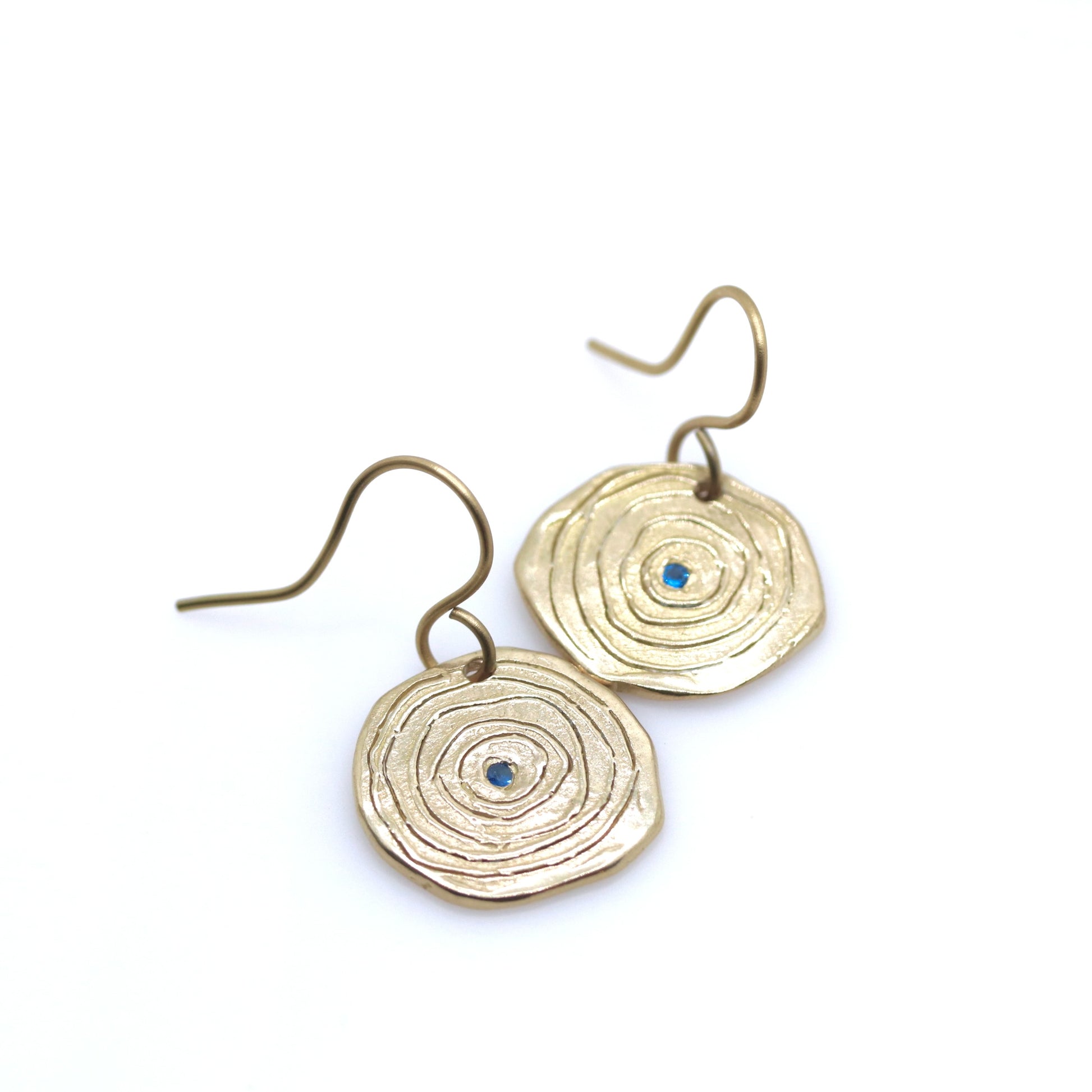 Gold circular earrings with blue stones on a white background