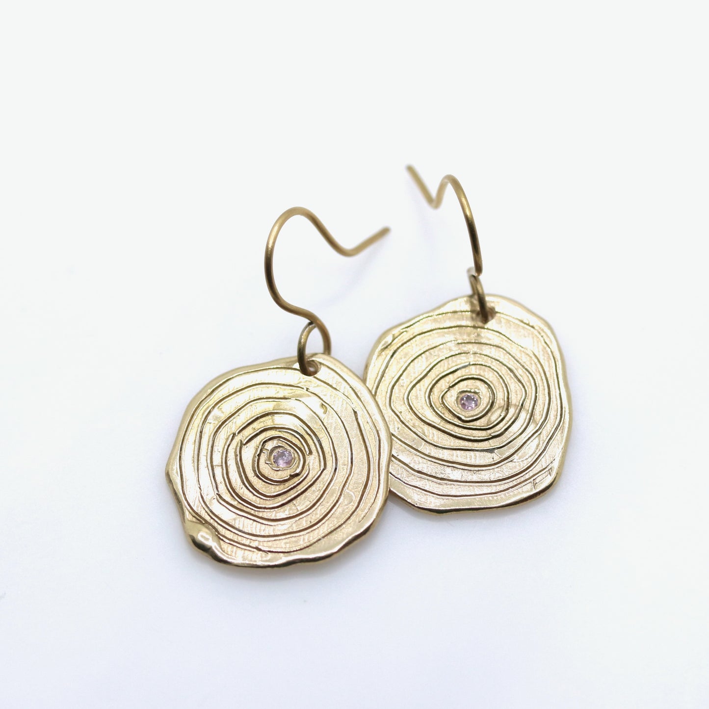 Gold circular earrings with a white background