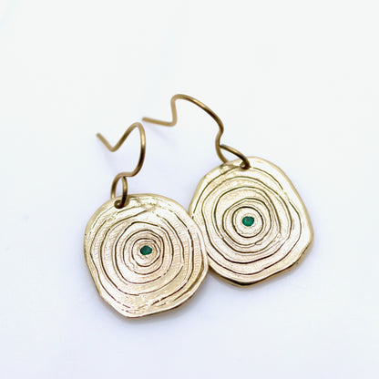 Gold circular earrings with green stones on a white background
