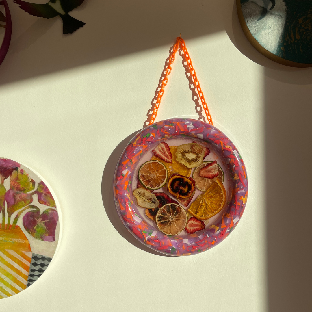 Decorative wall hanging with dried fruits and colorful resin on a light background