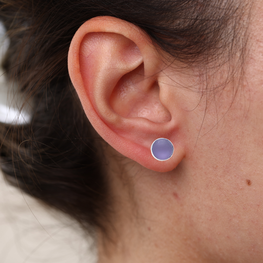Close-up of an ear wearing a purple earring with blurred background