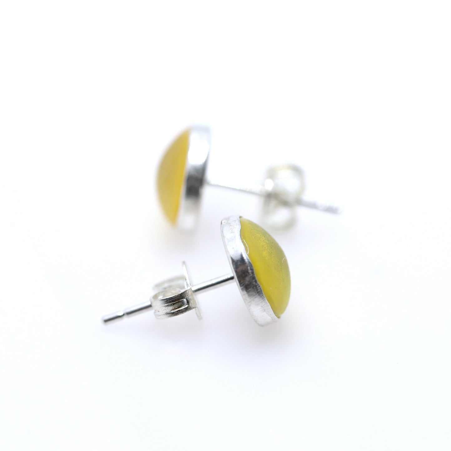 Pair of yellow resin earrings with silver bases on a white background