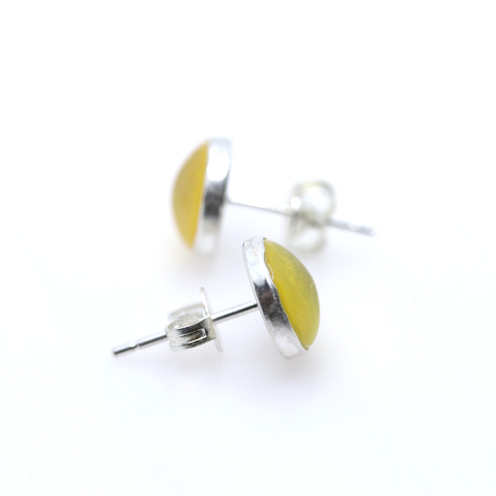 Pair of yellow resin earrings with silver bases on a white background