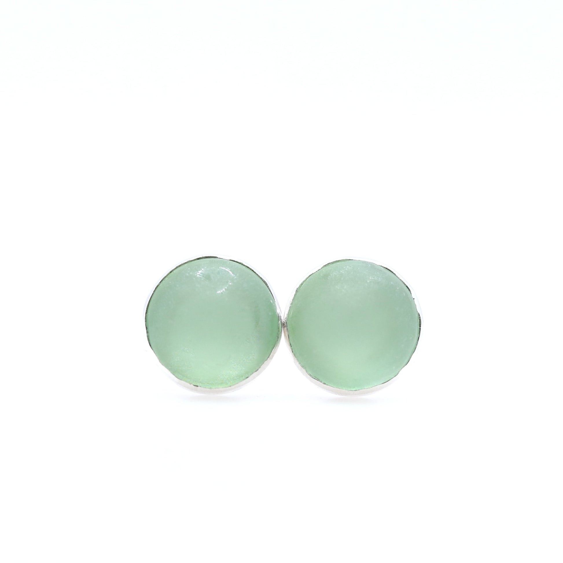 Pair of light green round earrings on a white background