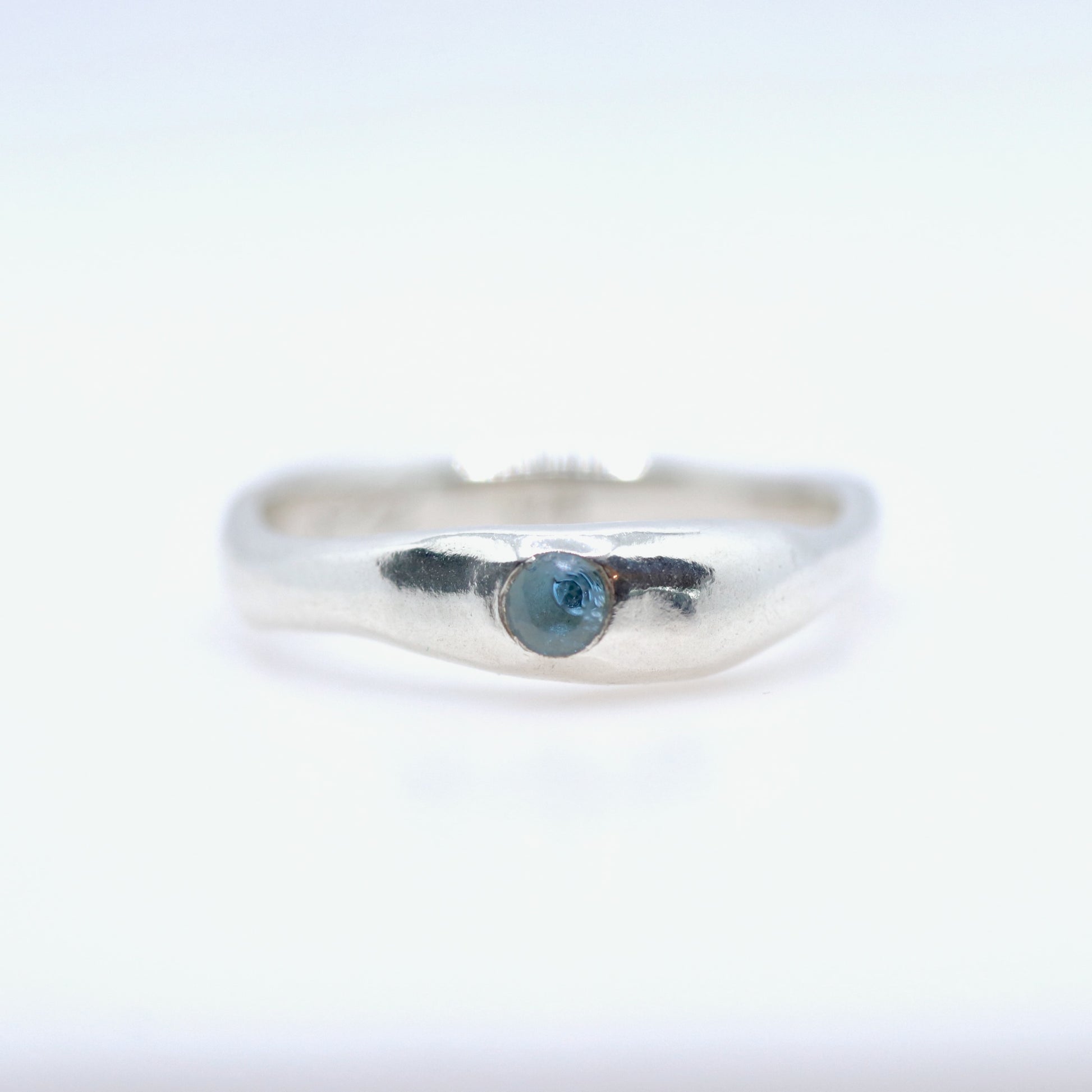 Silver ring with a blue gemstone on a white background