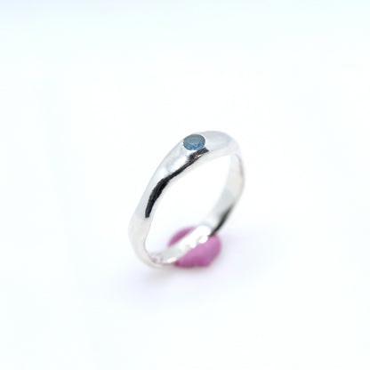 Silver ring with a blue gemstone on a white background