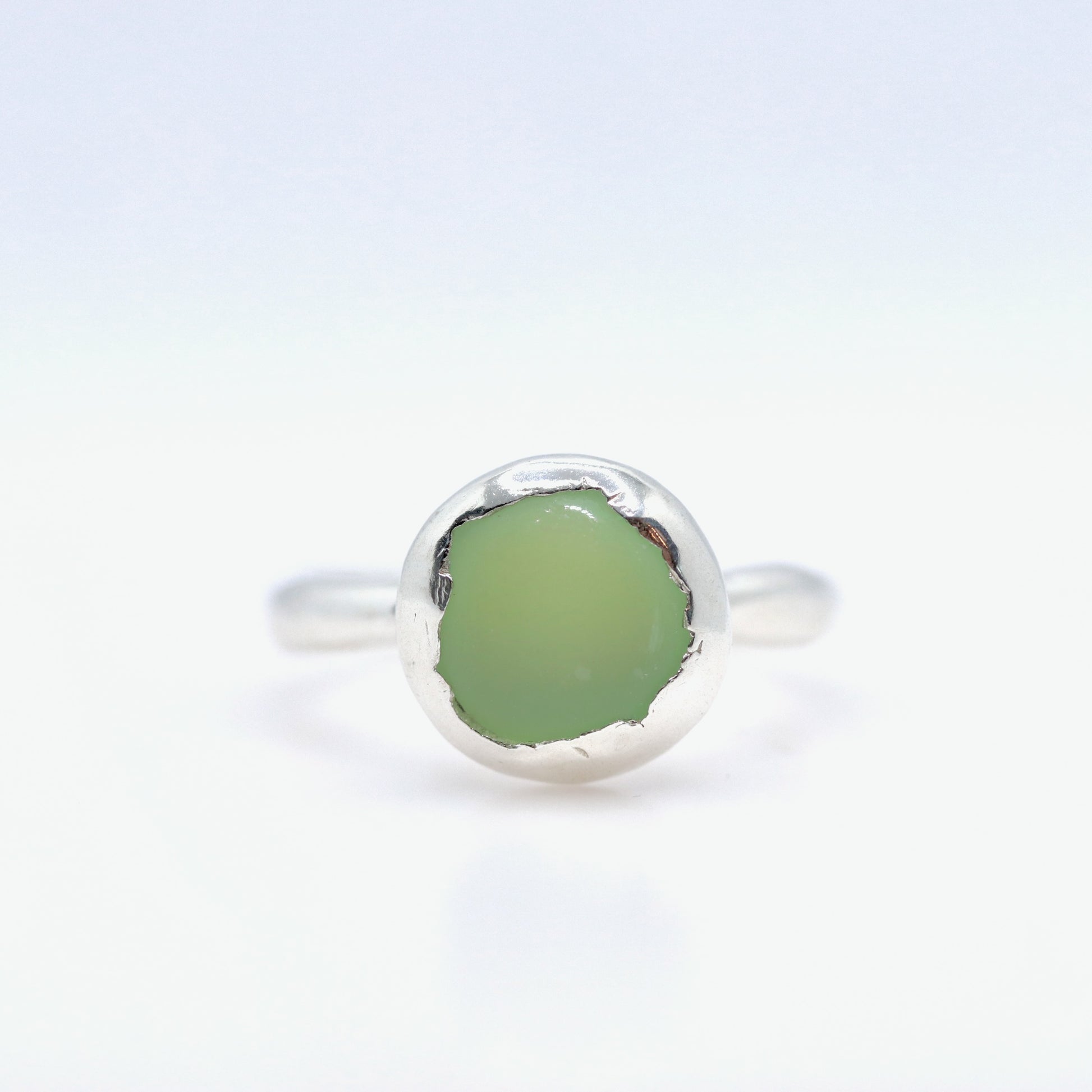 Silver ring with a green stone on a white background