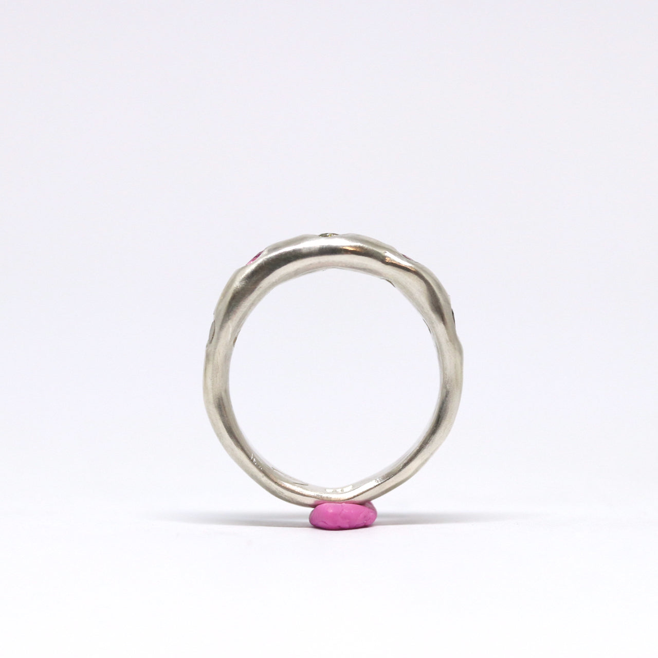 A sterling silver ring with five cubic zirconia in shades of pink and green.