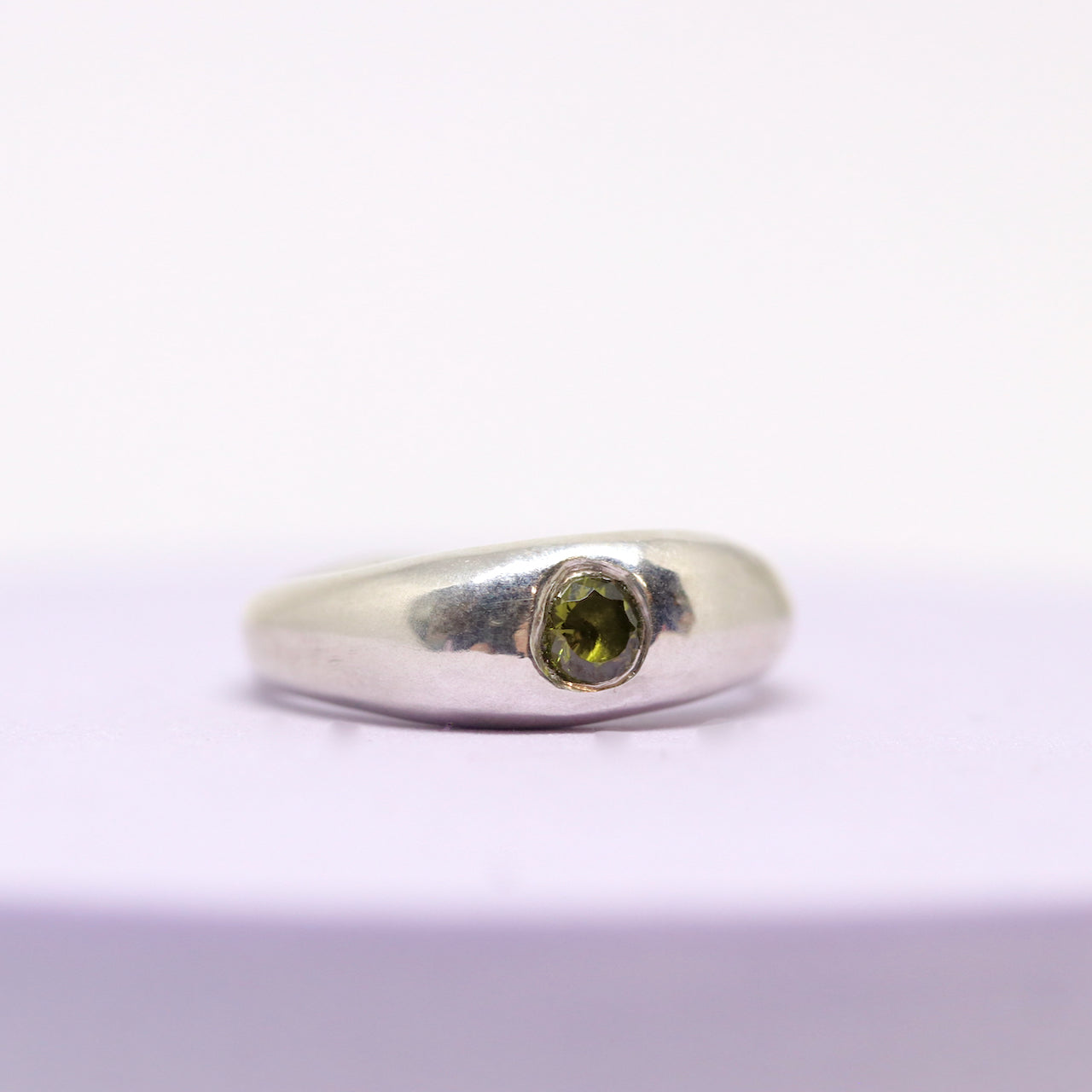 A sterling silver ring with one olive gem.