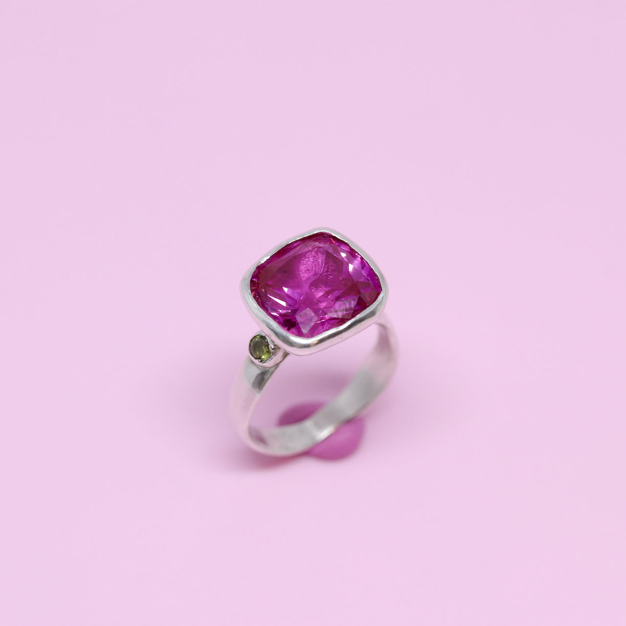 A big juicy pink cubic zirconia cocktail ring with two olive cubic zirconia on the shoulders.