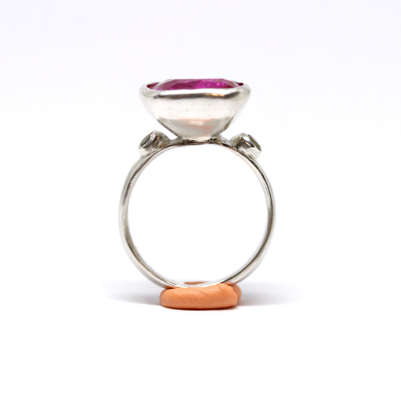 A big juicy pink cubic zirconia cocktail ring with two olive cubic zirconia on the shoulders.