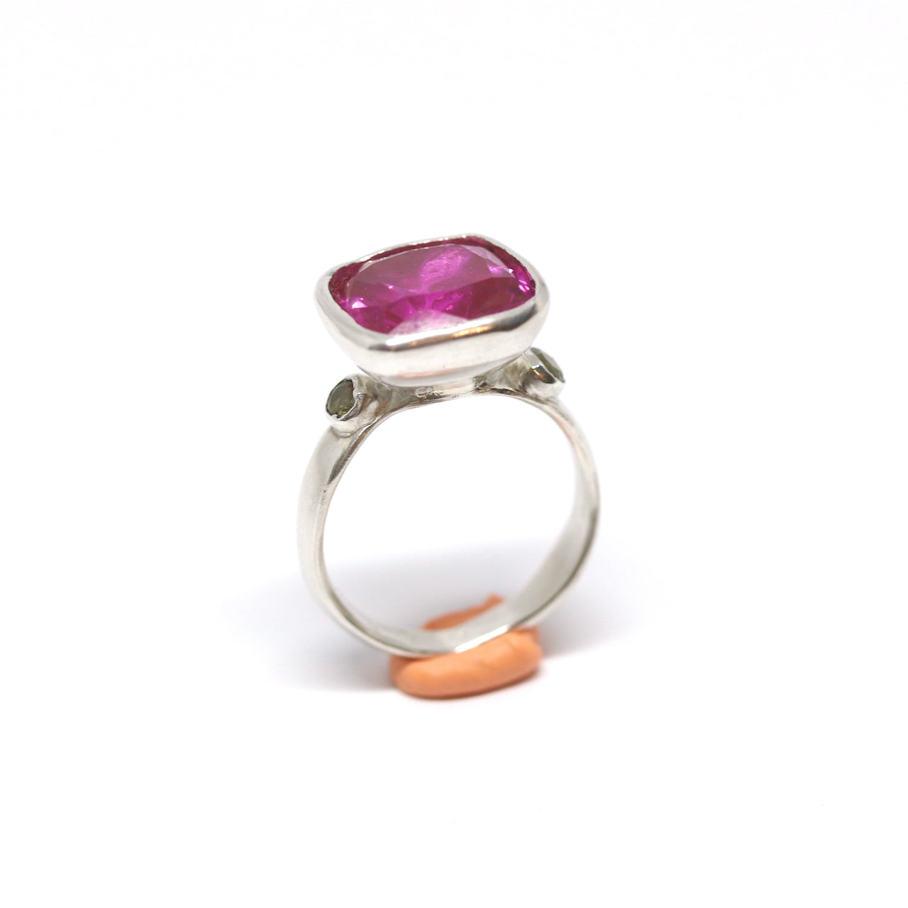 A big juicy pink cubic zirconia cocktail ring with two olive cubic zirconia on the shoulders.