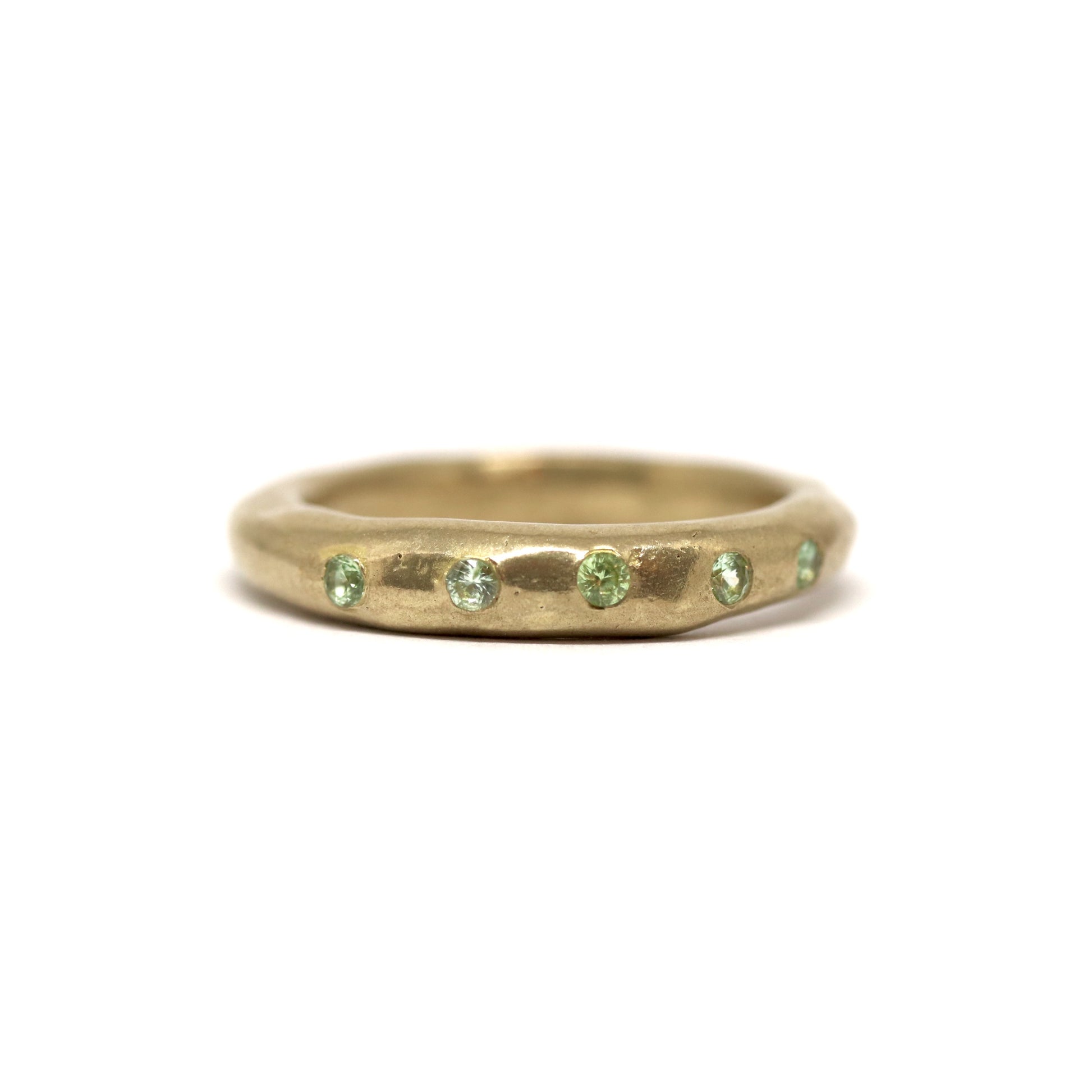 Bronze ring with green gemstones on a white background