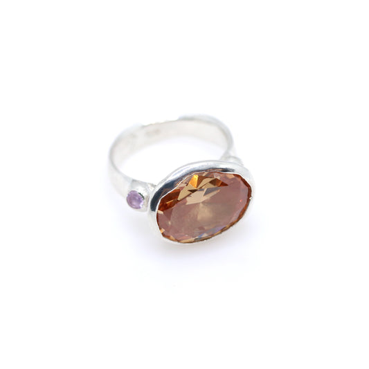 Silver ring with a large peachy gemstone on a white background. New Zealand made jewellery designer