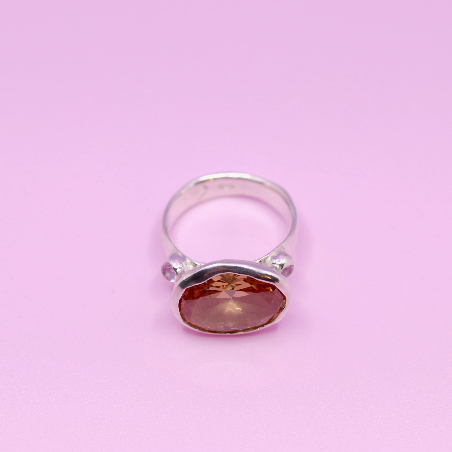 Silver ring with a peach gemstone on a pink background. New Zealand made jewellery designer