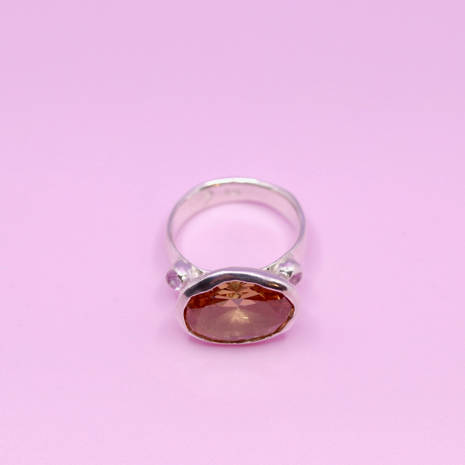 Silver ring with a peach gemstone on a pink background. New Zealand made jewellery designer