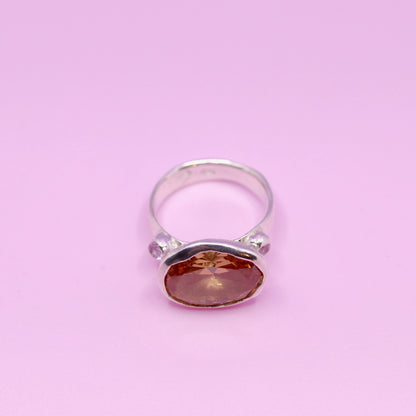 Silver ring with a peach gemstone on a pink background. New Zealand made jewellery designer