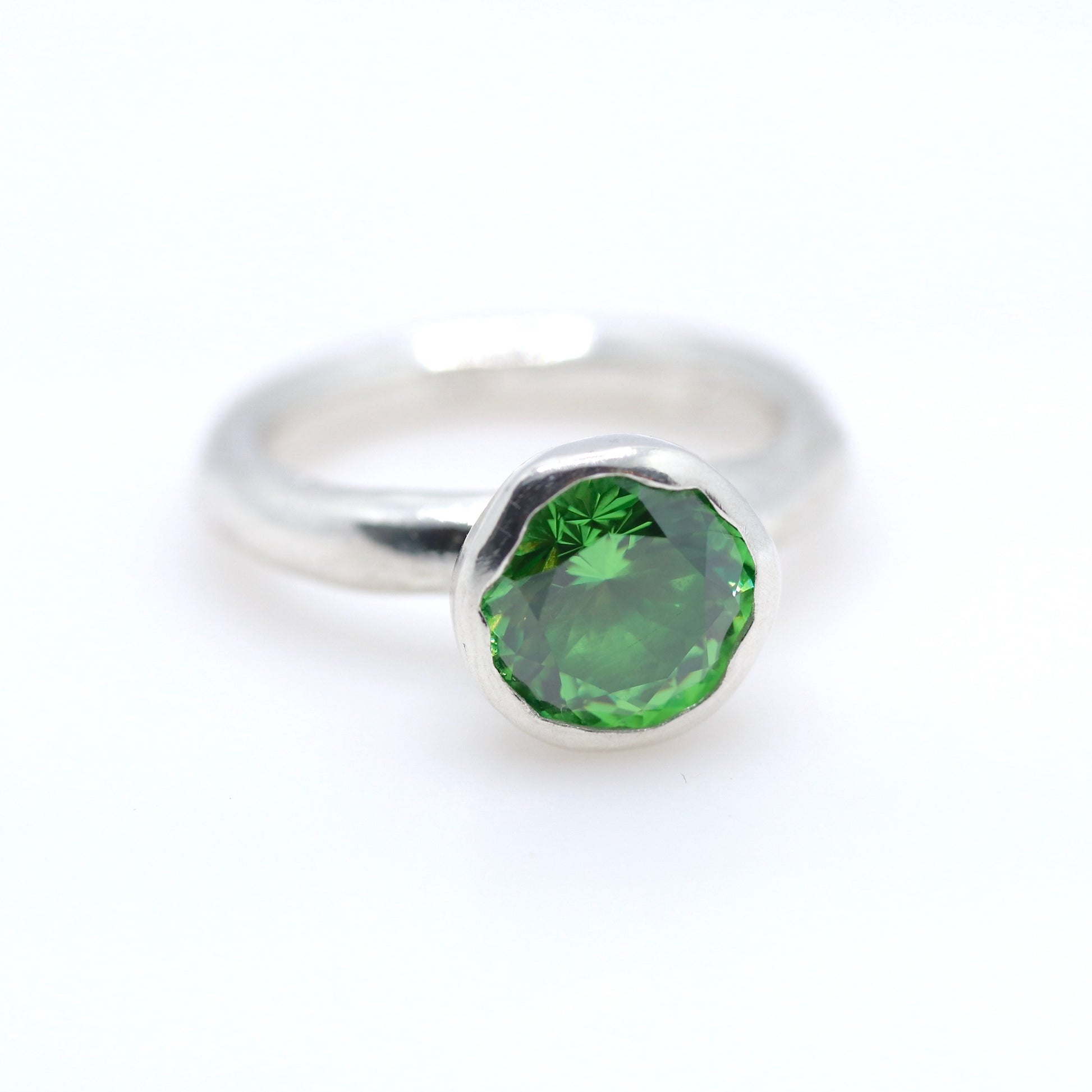 Silver ring with a tsavorite green gemstone on a white background