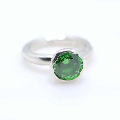 Silver ring with a tsavorite green gemstone on a white background