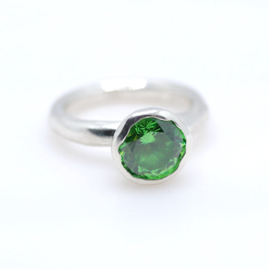 Silver ring with a tsavorite green gemstone on a white background