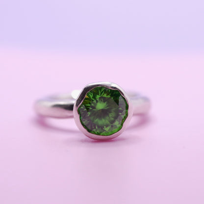 Silver ring with a tsavorite green gemstone on a pink background. New Zealand made jewellery designer