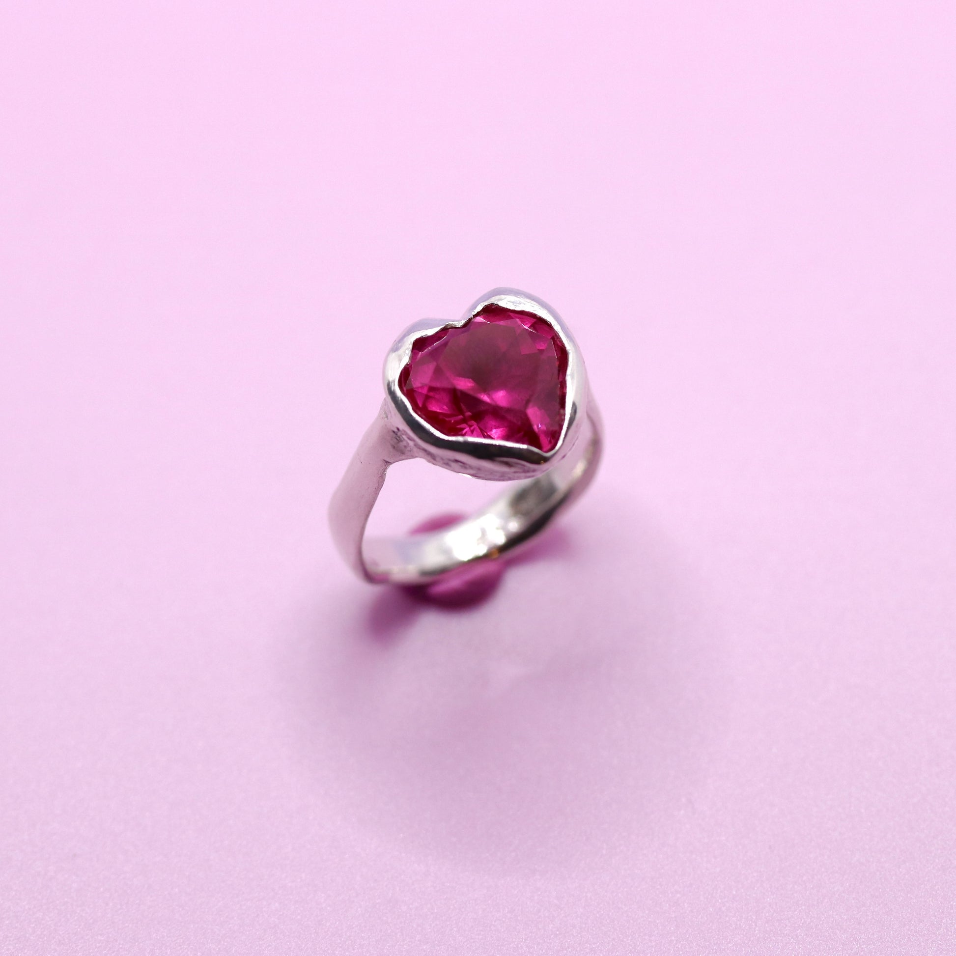 Silver ring with a heart-shaped pink gemstone on a pink background. New Zealand made jewellery designer