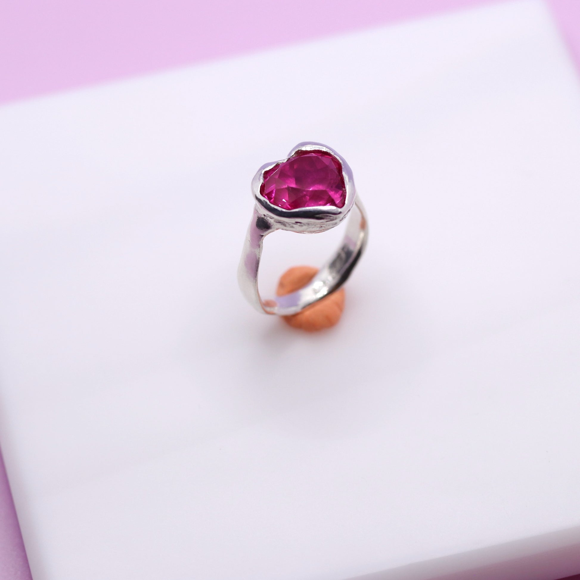 Silver ring with a heart-shaped pink gemstone on a white surface.New Zealand made jewellery designer