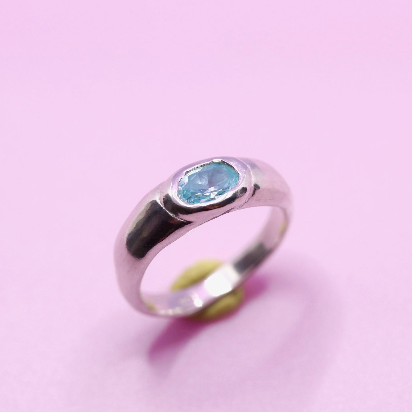 Silver ring with a aquamarine blue gemstone on a pink background. New Zealand made jewellery designer