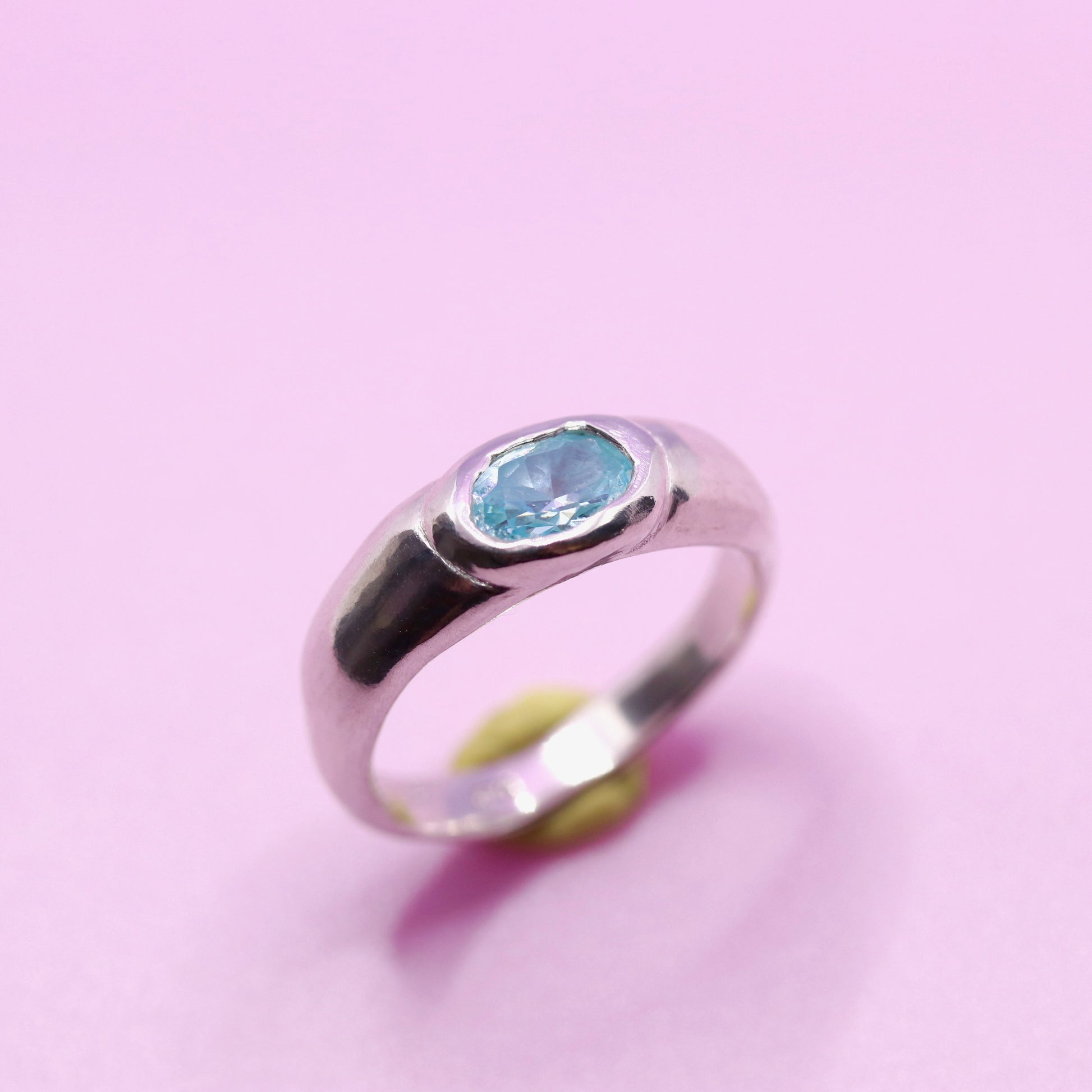 Silver ring with a aquamarine blue gemstone on a pink background. New Zealand made jewellery designer
