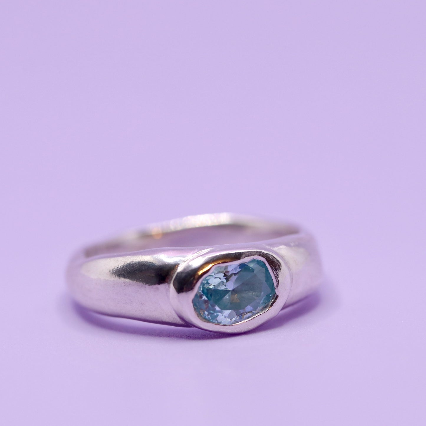 Silver ring with a aquamarine blue gemstone on a purple background. New Zealand made jewellery designer