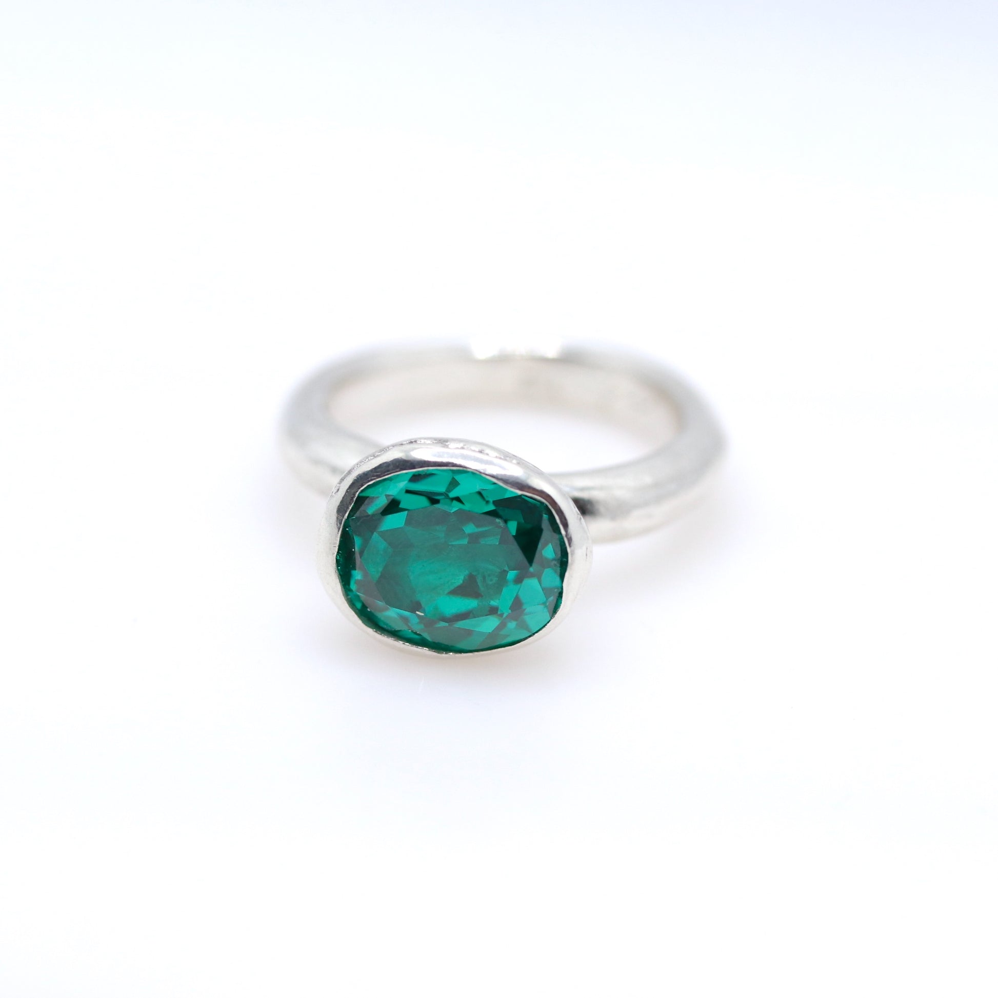 Silver ring with a paraiba green gemstone on a white background