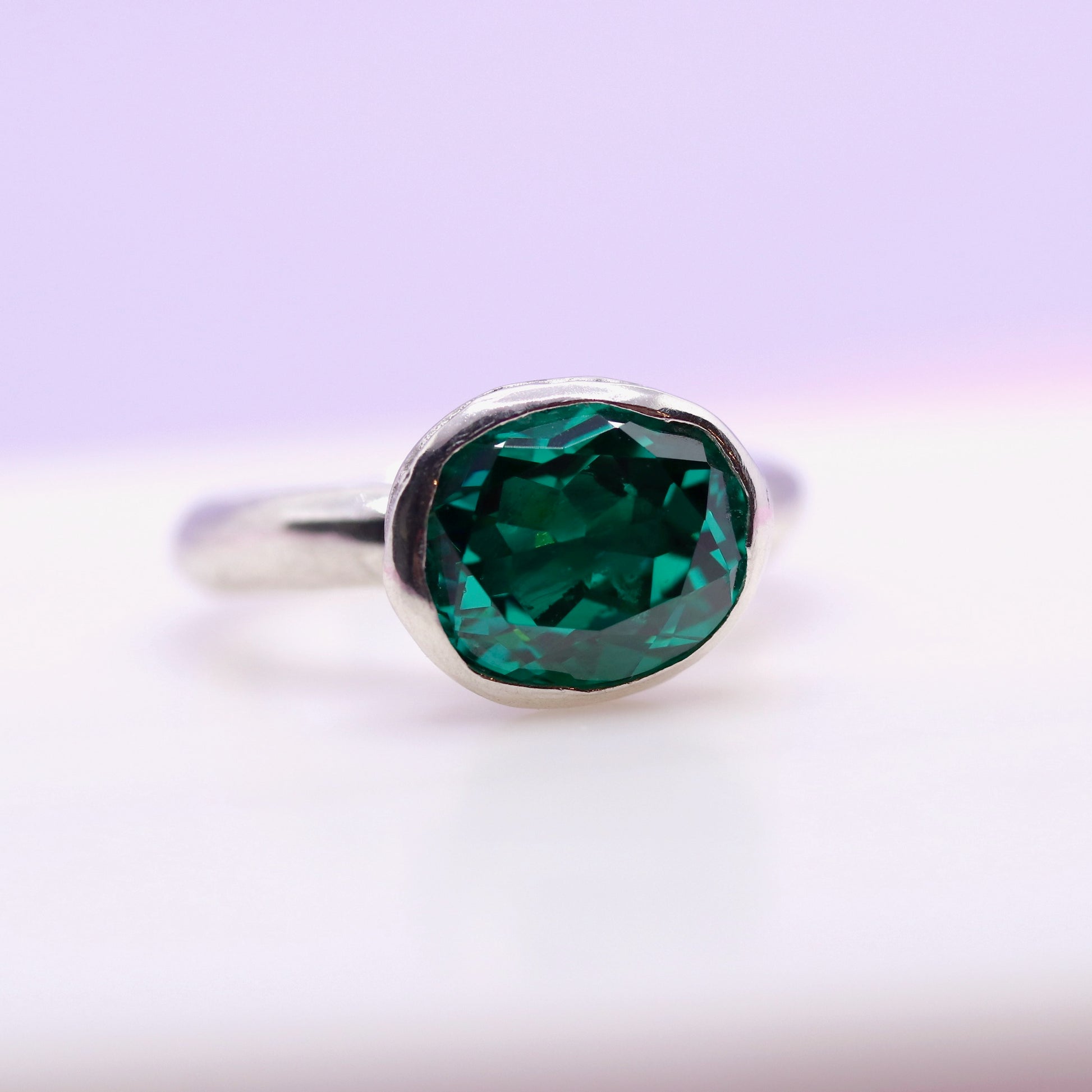 Silver ring with a paraiba green gemstone on a gradient background