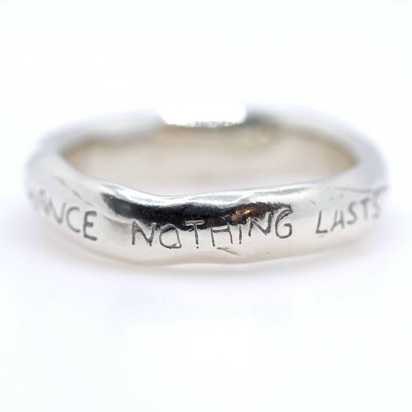 Silver ring with engraved text on a white background