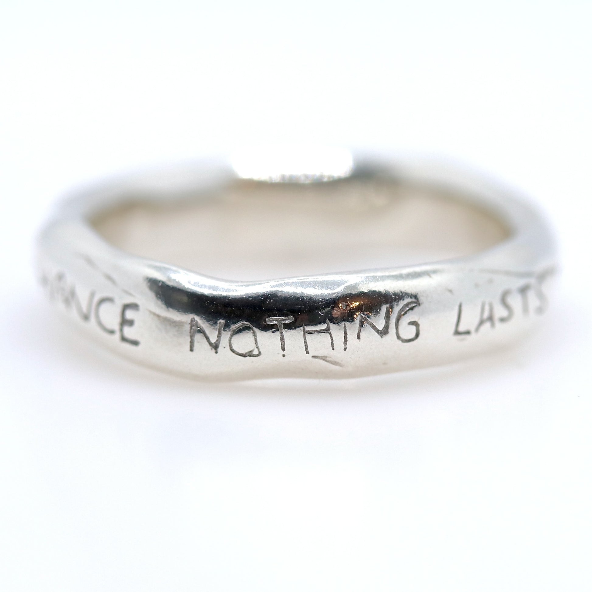 Silver ring with engraved text on a white background